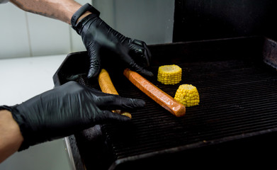 The chef cooking two hot dogs on a grill. Restaurant.