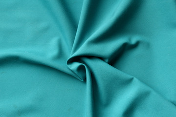 Abstract background in the form of crumpled fabric of a color of a sea wave, satin fabric of a wave.