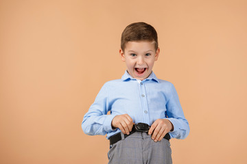 satisfied little child boy looking to camera on beige background. Human emotions and facial expression. copy space