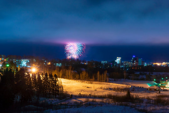 Fireworks in the night sky over city in winter landscape