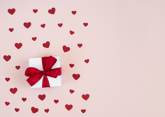 Valentines day composition. Greeting card with a gift and confetti hearts on a pastel pink background. Valentines day concept.