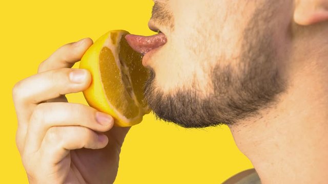 Male Tongue Licking Sliced Orange Imitating Cunnilingus on Yellow Background. Simulation of oral sex. Sexual Fruit Eating. Imitating oral sex.
