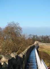 Fototapeta premium a view along the pedestrian walkway on historic medieval city walls in york surrounded by trees and city buildings