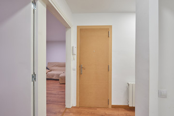 entrance of an apartment, all white and the door brown