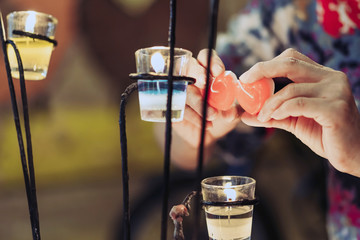 A red heart shaped candle in a woman's hand with candlelight in many small glass cups. A valentine's day background.