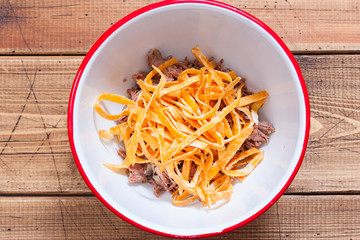 Step-by-step salad preparation with boiled beef and egg pancakes, step 2 - adding chopped egg pancakes to the salad, top view, horizontal