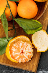 a plate with some tangerines and cutting board on marble background