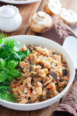 Salad with smoked chicken and fried champignons in a white plate on a wooden table with fresh herbs, selective focus