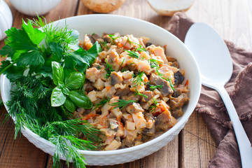 Salad with smoked chicken and fried champignons in a white plate on a wooden table with fresh herbs, selective focus