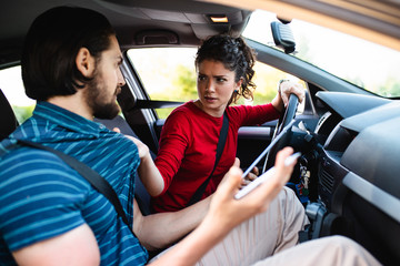 Driving school or test. Beautiful young woman learning how to drive car together with her instructor.