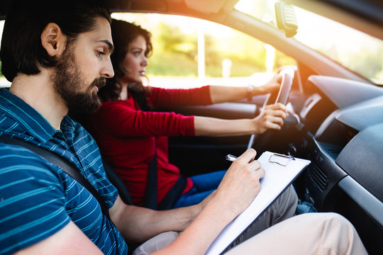 Driving school or test. Beautiful young woman learning how to drive car together with her instructor.