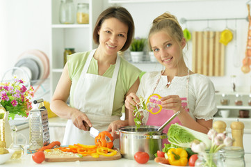 Portrait of cute little girl with mother cooking