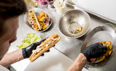 The chef cooking hot dog on a grill. Restaurant.