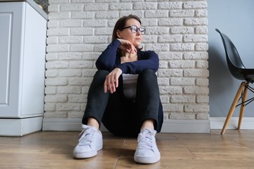 Depressed mature woman sitting on the floor at home