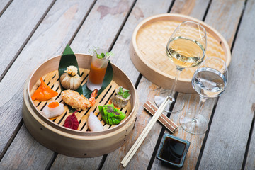 Several different traditional Chinese dimsum dumplings in a wooden basket cooked for guests on a wooden table in a restaurant.