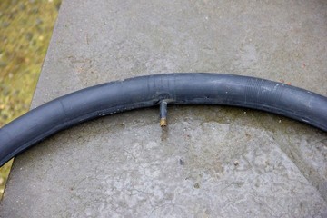 A portrait of part of a blown up inner tire and its valve on a wet rock ready to be used to replace another flat tire.