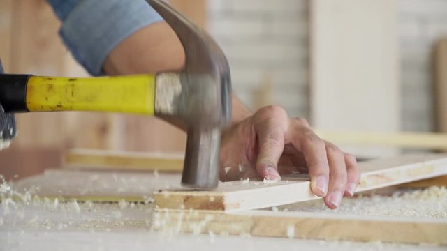  Close up of a man hammering a nail, DIY repairing the furniture, renovation concept.
