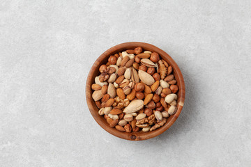 Different types of nuts in a wooden bowl, top view.