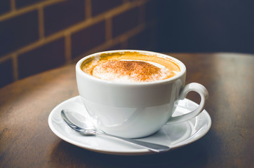close up modern hot black coffee the cappuccino on wood background with coffee bubble foam pattern and texture in white cup looking and feel so delicious on glasses table in coffee shop.