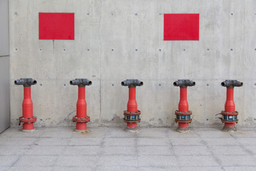 Fire Hydrant poles in front of bare concrete wall with blank red sign.