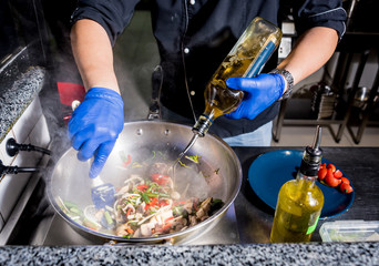 Chef cooking pasta with vegetables in pan. Italian style cuisine. Restaurant.