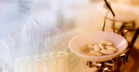 Fototapeta premium Medicine concept: White pills on mechanical balance with a blurred background of a scientist is researching in the laboratory.