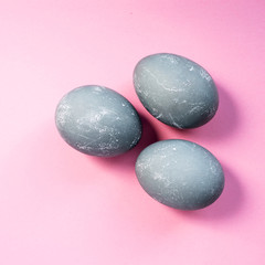 Three gray colored easter eggs on pink background. Top view, flat lay. Copy space. Happy Easter concept.