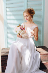 portrait of a beautiful girl with blue eyes and white hair with a bouquet of flowers and a white dress