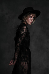 Fototapeta na wymiar Young beautiful blonde woman in a black hat and dress.