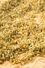 Heap of uncooked, raw freekeh or firik, roasted wheat grain, on brown packing paper
