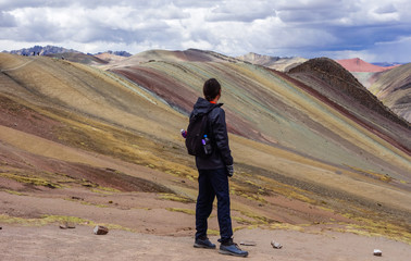 Cusco/Peru: boy admires the beautiful view on the Palccoyo rainbow mountains. Colorful landscape in the andes