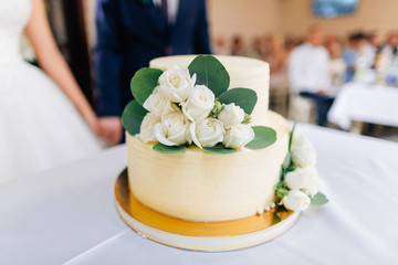 Wedding cake decorated with flowers,newlyweds on background