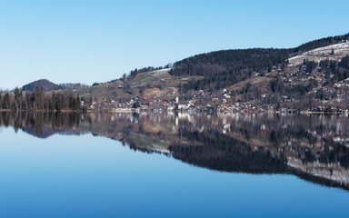 Schliersee in Oberbayern. Panorama von Fischhausen am Horizont mit lichtreflexion am see, Ort im Winter mit Kirchdorf Sankt Sixtus