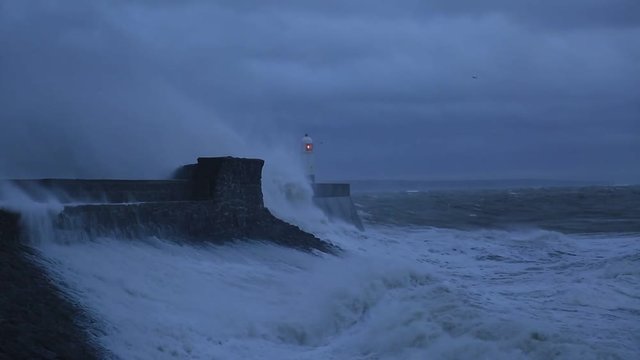 Porthcawl lighthouse and pier in the jaws of a storm on the coast of South Wales, UK.