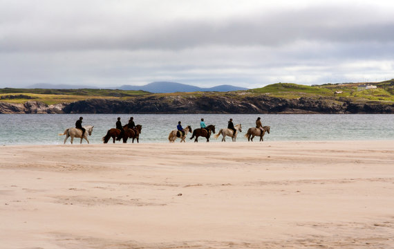 Row of horse riders on Dunfanaghy beach, County Donegal, Ireland.