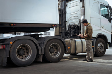 Truck Driver is Checking the Truck's Safety Maintenance Checklist. Lorry. Inspection Semi Truck Wheels and Tires. Warehouse Cargo Shipping. Loading Freight Truck Transport Logistics.