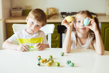 Obraz na płótnie Canvas Easter holiday - cute cheerful children holding decorated eggs at home. Little girl and boy - having fun and celebrating feast