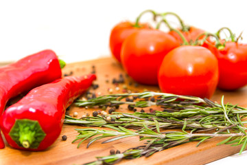 Close-up photo of red hot peppers, tomatoes with pepper peas and rosemary at the cutting board. Vegan food concept. Agriculture and harvesting.