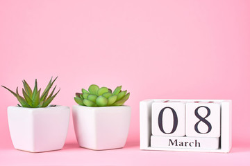 Women's Day concept. Wooden calendar block with date 8 march and plant on the pink background with copy space