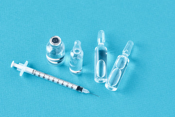 Syringes and medicine bottles with medication on a blue background