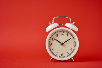 White retro alarm clock on the red background with copy space. Time concept