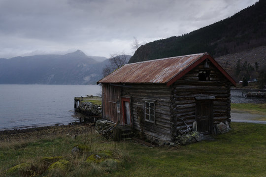 Old and remote cabin on the coast of beautiful norwegian fjord in More og Romsdal area. Old house looks a bit scary. Perfect place for shooting horror movie. Moody atmosphere around.