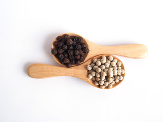 Top view of white pepper seeds and black peppercorn in wooden spoon isolated on white background.