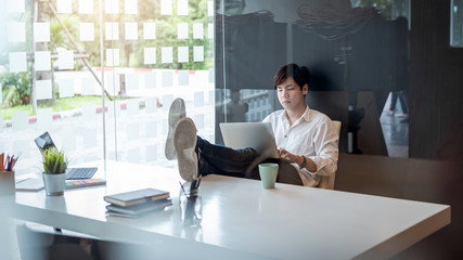 Happy young architect sitting with feet on table work in modern office.