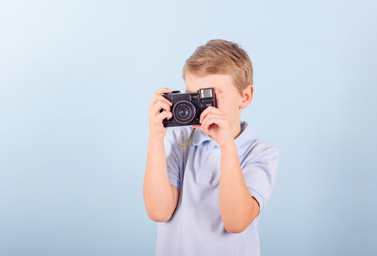 a child with a retro camera on a blue background, a creative smart blond boy in a blue Polo shirt