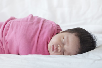 Obraz na płótnie Canvas Closeup a baby sleeping comfortably on the bed