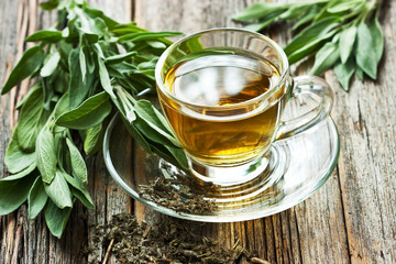 Sage tea  in glass mug and sage leaves on wooden table