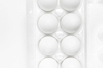 White chicken eggs in white packaging on light background top view flat lay copy space. Eggs in box, natural healthy food and organic farming concept. Creative food minimalistic background, Easter