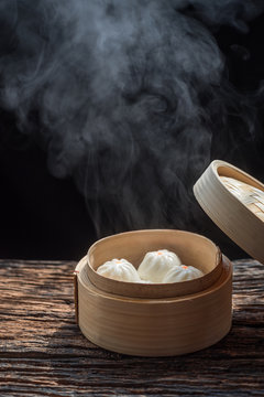 Steam and smoke of hot chinese steamed bun in traditional bamboo steamer on dark background.selective focus.hot food concept