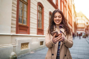 Street life. Business woman with phone on the street. Beautiful young woman with smart phone outdoors at sinlight. Beautiful city girl with smart phone.